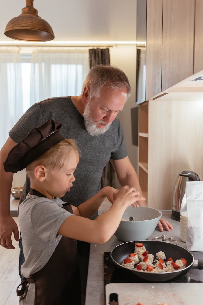 A grandfather helps his young grandson prepare food in a modern kitchen, creating lasting family memories.